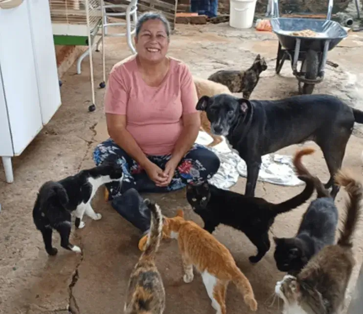 Protetor sentado no chão com três cães resgatados ao seu redor